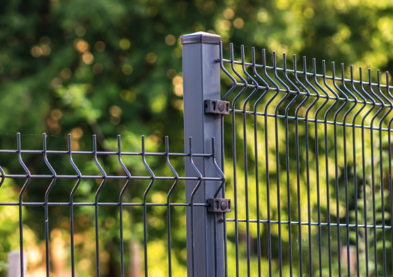 Modern metal fence with clean straight lines and strong post. Green blurred vegetation in the background.